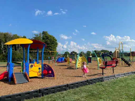 A vibrant playground shows a happy child enjoying safe, slip-resistant surfacing installed by J&P Coatings.