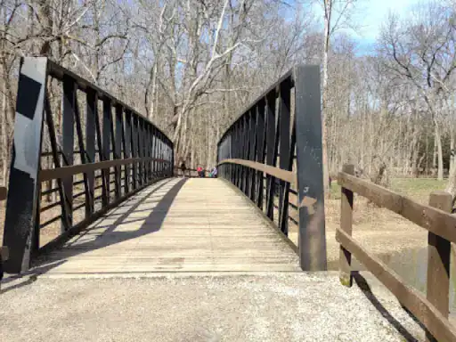 People walk across a footbridge on a sunny day, possibly talking about J&P Coatings for basement floor sealing.