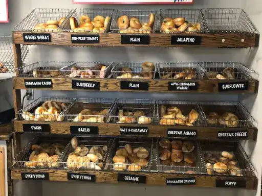 Fresh bagels in labeled baskets sit on shelves, showing a clean space with quality floors from J&P Coatings. Alt text: Quality floors by J&P Coatings under bagel baskets on shelves.