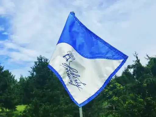 The image shows a flag waving outside, representing Liberty Hockey, with the J&P Coatings building seen behind it.