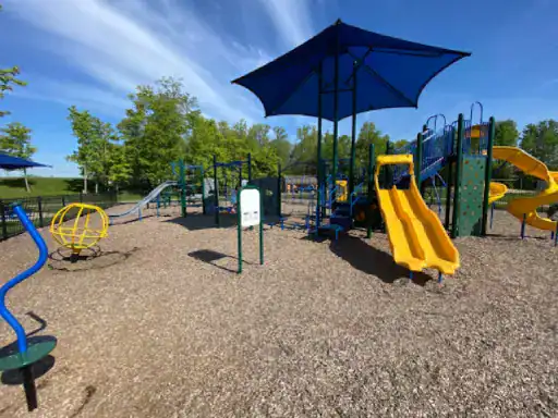 Children enjoy playing on creative playground equipment under a blue shade canopy, inspiring fun patio coatings by J&P Coatings.