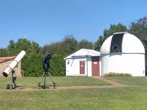 Two telescopes are set up outside an observatory with J&P Coatings’ patio work nearby, ready for viewing under open skies.