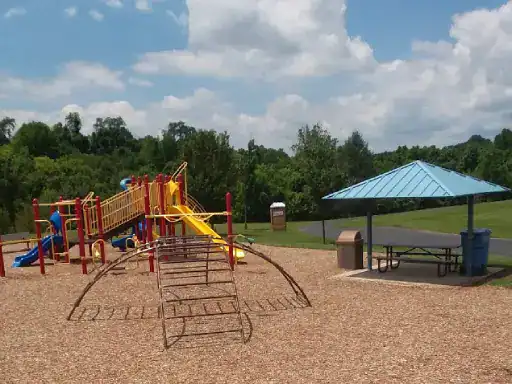 A playground sits next to a picnic area where J&P Coatings have made the concrete patio tough and nice-looking. Trees and grass surround the space, making it inviting for families.