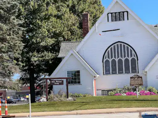 A well-kept church stands on neat grass with flowers. The entrance area looks improved after updates by J&P Coatings.