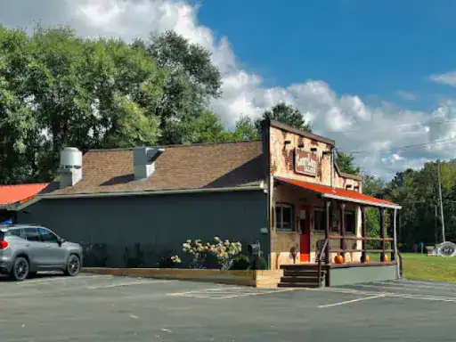 A cozy restaurant with a red roof and pumpkins on the porch shows the strong patio coatings from J&P Coatings. Trees are in the background.