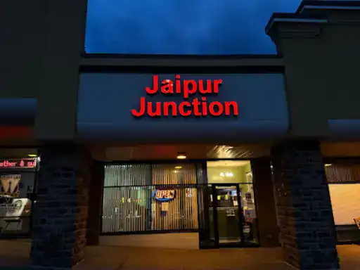 A restaurant with a welcoming atmosphere and a bright sign shows J&P Coatings’ quality patio work nearby, inviting customers inside.