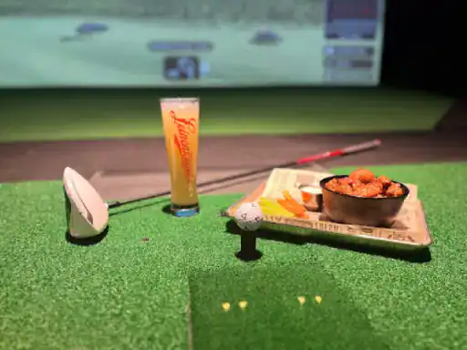 People enjoy golf, food, and drinks together in a fun indoor entertainment space. J&P Coatings makes the floor strong and safe for this kind of area.