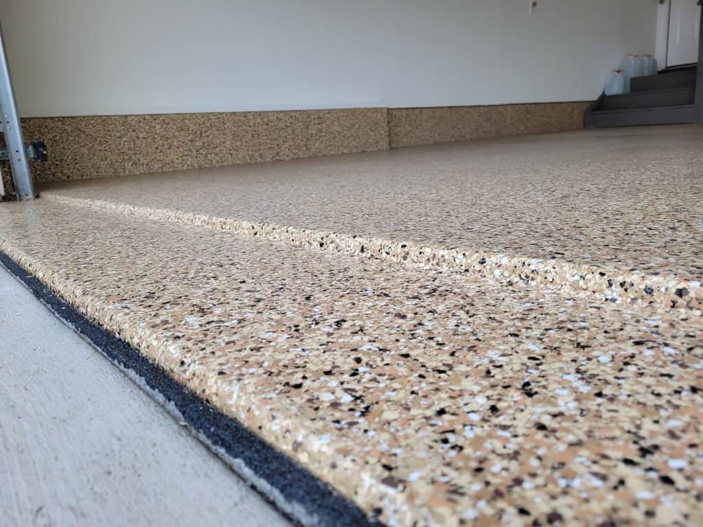 A smooth, beige epoxy floor by J&P Coatings shows a strong, stain-resistant surface. This flooring is a good option for garages or basements.