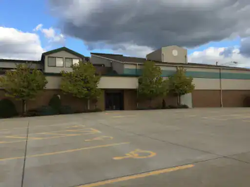 A parking lot in good condition is in front of a building with tan and green trim. This shows the quality work of J&P Coatings.