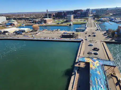 Image conveys a busy waterfront area with buildings, boats, and a nearby bridge painted for pedestrians. J&P Coatings helps keep these public spaces protected and looking their best.
