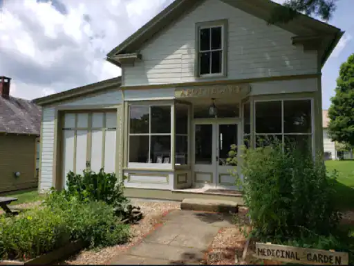 A historic house looks inviting with its updated patio from J&P Coatings. The garden and sign in front highlight its welcoming feel. Alt text: A classic home with a modern patio finish by J&P Coatings and a garden sign out front.