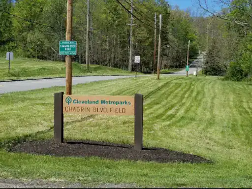A wooden sign shows the name of a local park where people enjoy the outdoors. J&P Coatings often helps protect nearby patios in this area.