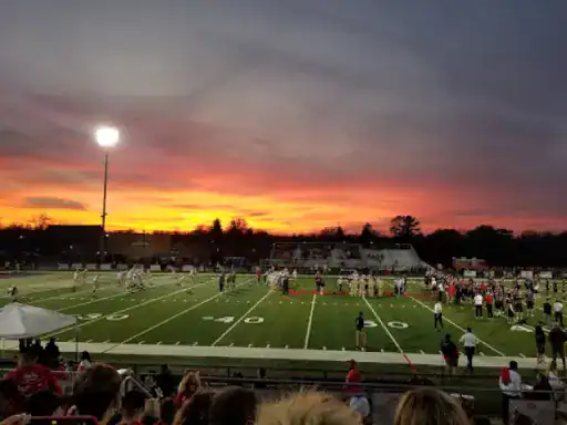 A high school football game takes place as fans cheer and bright stadium lights shine. The strong field reminds you of the long-lasting basement floors J&P Coatings creates. Alt text: Fans watch a football game, like how people enjoy durable floors from J&P Coatings.