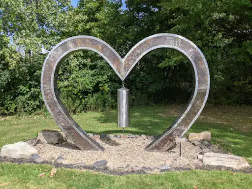 The image shows a unique heart sculpture outdoors, highlighting J&P Coatings&rsquo; creativity and skill with metalwork.