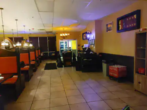 A restaurant shows J&P Coatings’ work, with comfortable orange booths and shiny floors that look well protected. Hanging lights make the space cozy, and a counter sits at the back. The room feels organized, with shelves and storage along one wall. Alt text: Restaurant showing J&P Coatings floors and seating in a welcoming setting.