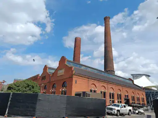 J&P Coatings is working at a big factory building. A company truck is parked outside behind a fence. The setting looks busy and safe.