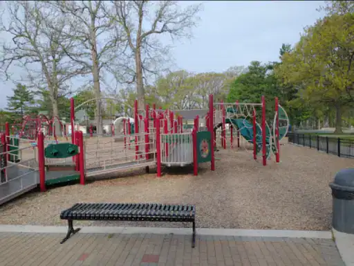 A playground designed for fun and safety is shown, with a sturdy bench from J&P Coatings inviting visitors to rest and enjoy the area.