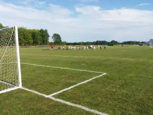 A group gathers on a soccer field while J&P Coatings signage shows community support for local sports.