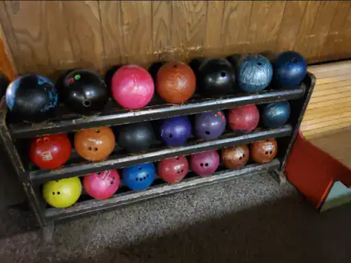 This image shows a variety of colorful bowling balls on a rack at a bowling alley. It conveys how J&P Coatings can offer concrete patio coatings in many vibrant colors to help bring fun and energy to outdoor spaces.