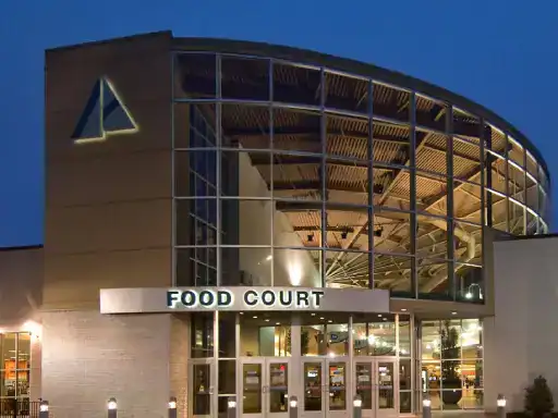 The building&rsquo;s entryway is improved by J&P Coatings&rsquo; concrete patio coatings, giving the food court a welcoming look at night. Through the large windows, you can see inside the food court. Alt text: Food court entrance with J&P Coatings&rsquo; concrete patio improving appearance at night.