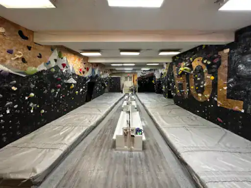 The image shows a modern bouldering gym. J&P Coatings provided a smooth, safe concrete floor that helps climbers stay protected. The gym appears bright and welcoming, with special touches to make climbing enjoyable. Alt text: A bouldering gym with quality flooring applied by J&P Coatings, designed for safety and fun.