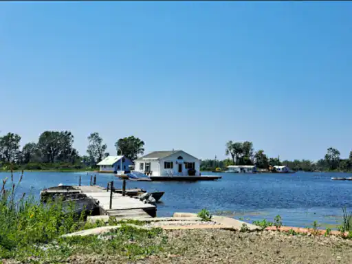 A floating house sits on a peaceful lake, with nearby homes featuring basement work by J&P Coatings.