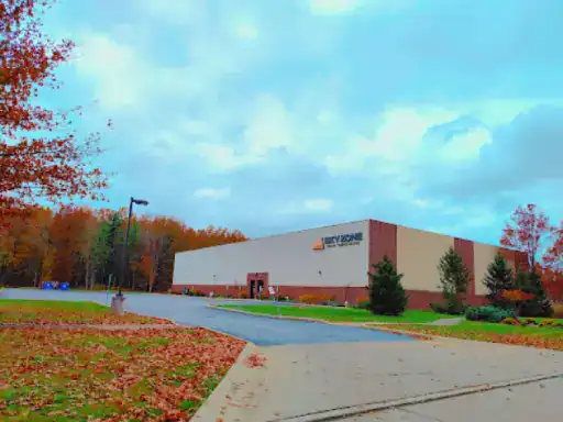 This image shows the outside of a Sky Zone building in autumn. The area in front, including the lot and sidewalk, would be good places for J&P Coatings to provide concrete sealing services. Alt text: Sky Zone exterior with nearby sidewalk and lot suited for J&P Coatings concrete sealing.