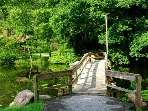 A peaceful park with a bridge over a calm pond shows how J&P Coatings can help make outdoor spaces strong and welcoming.