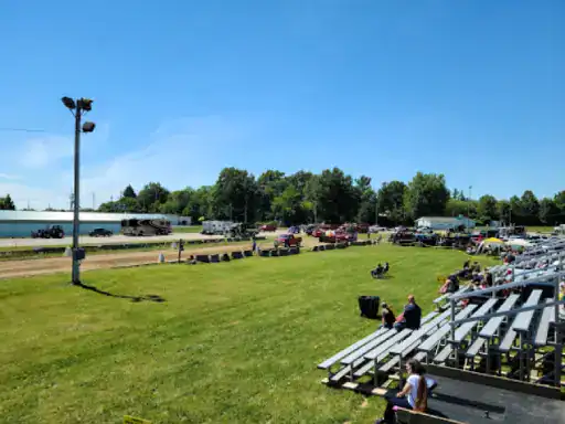 A dirt racetrack hosts a small crowd and parked vehicles. This lively, open area is a great place for J&P Coatings&rsquo; reliable flooring services.