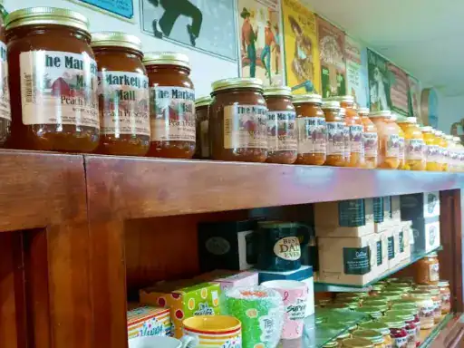 A shelf holds jars of jams and preserves in a warm, inviting store. The space feels friendly, like the comfort J&P Coatings brings to homes.