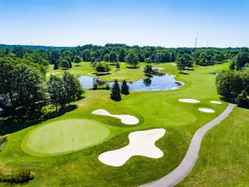 A golf course with a smooth cart path coated by J&P Coatings, showing a well-kept and inviting place to play.