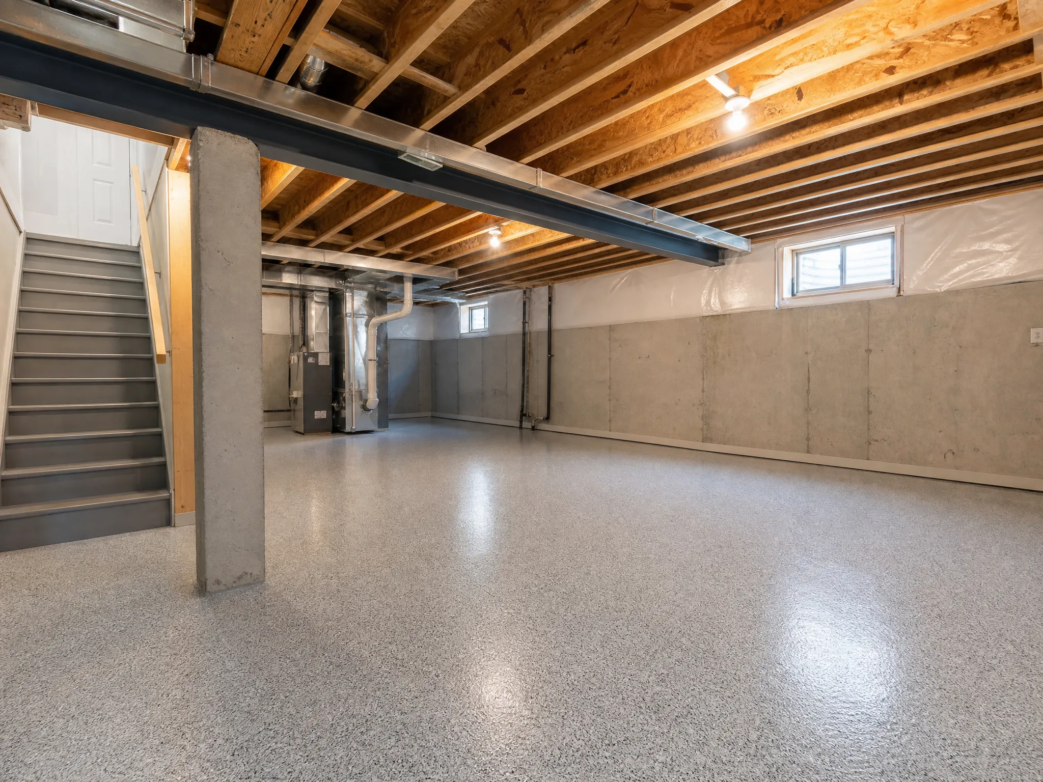 J&P Coatings shows an unfinished basement ready for renovation, with natural light entering through small basement windows.