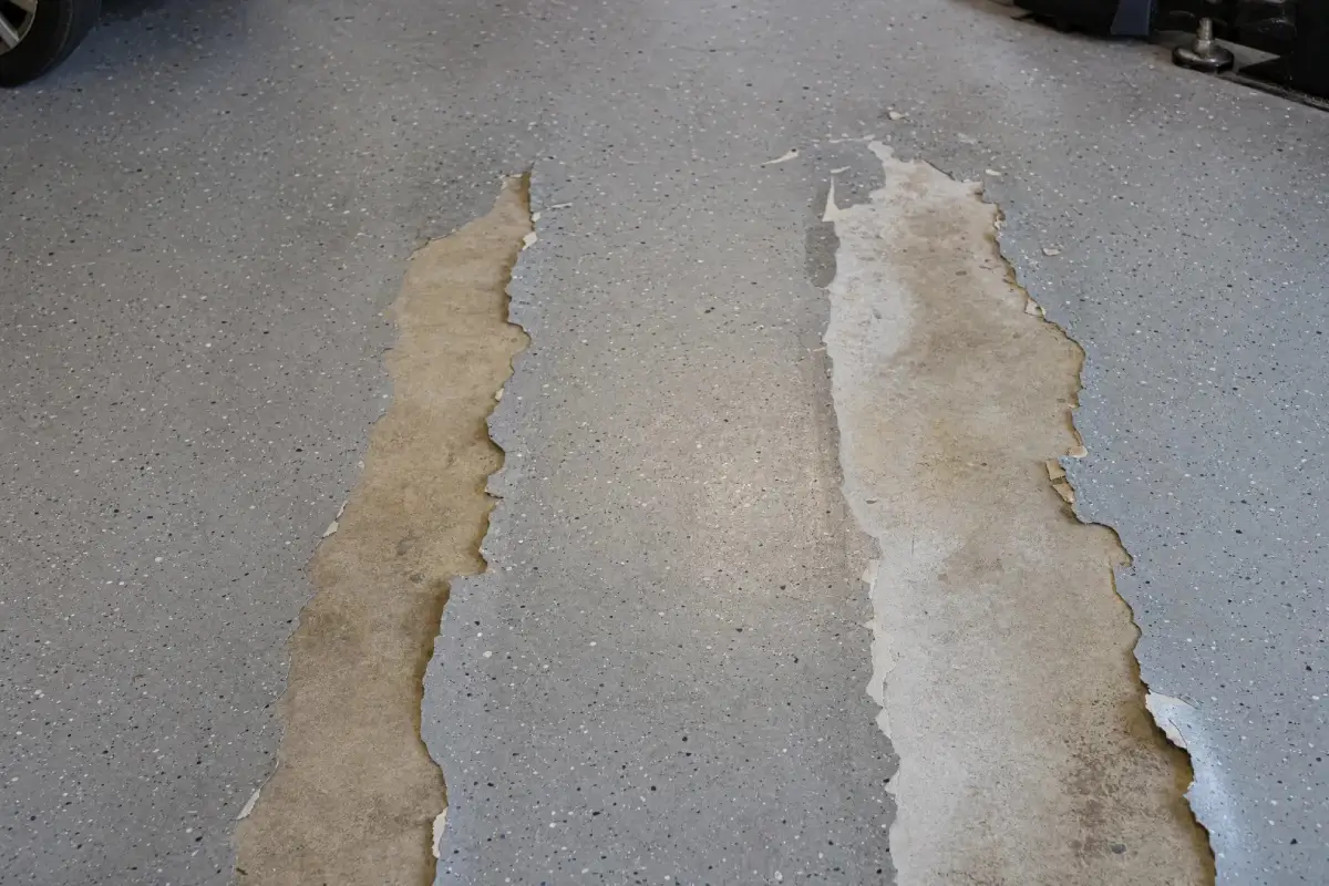 J&P Coatings floor shows peeling areas exposing bare concrete, suggesting the need for repair or better durability.