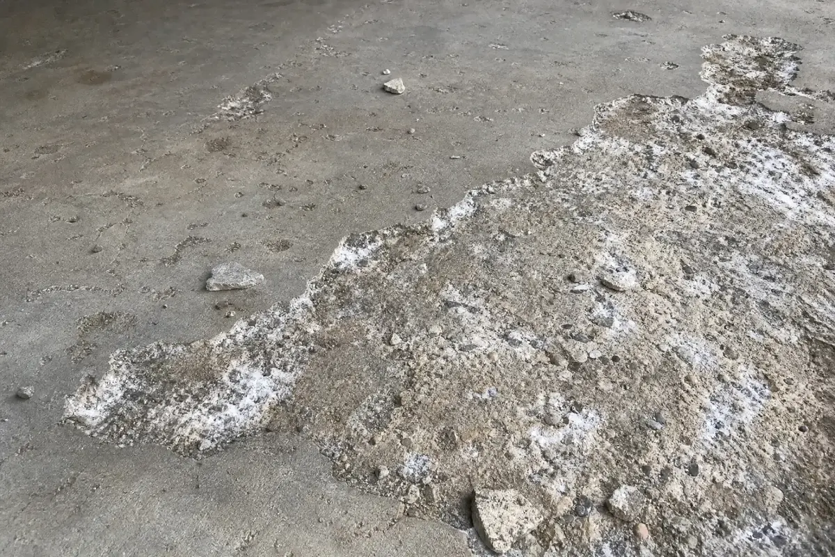 J&P Coatings shows a worn concrete surface that needs repair due to visible signs of damage and age.