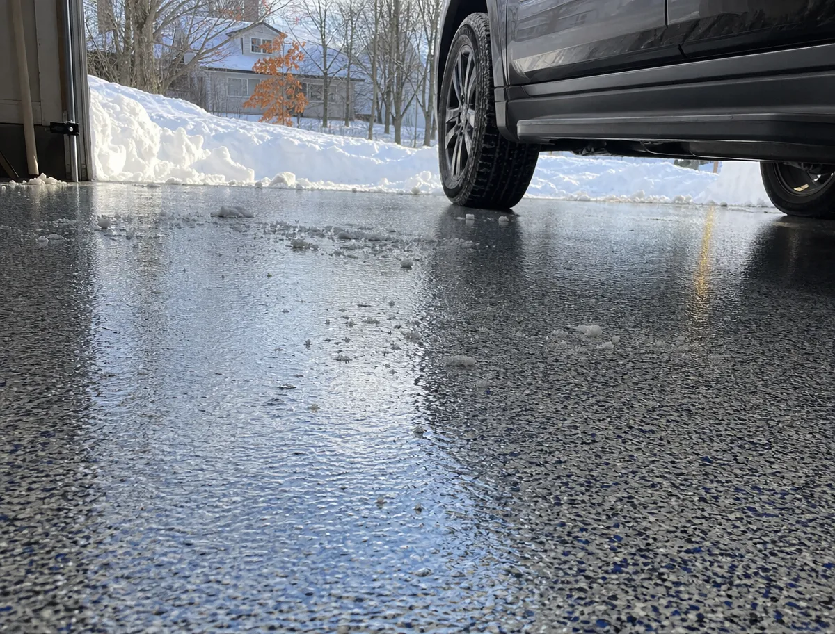 J&P Coatings shows a garage floor where snow and water make it look slippery, showing why strong coatings matter.