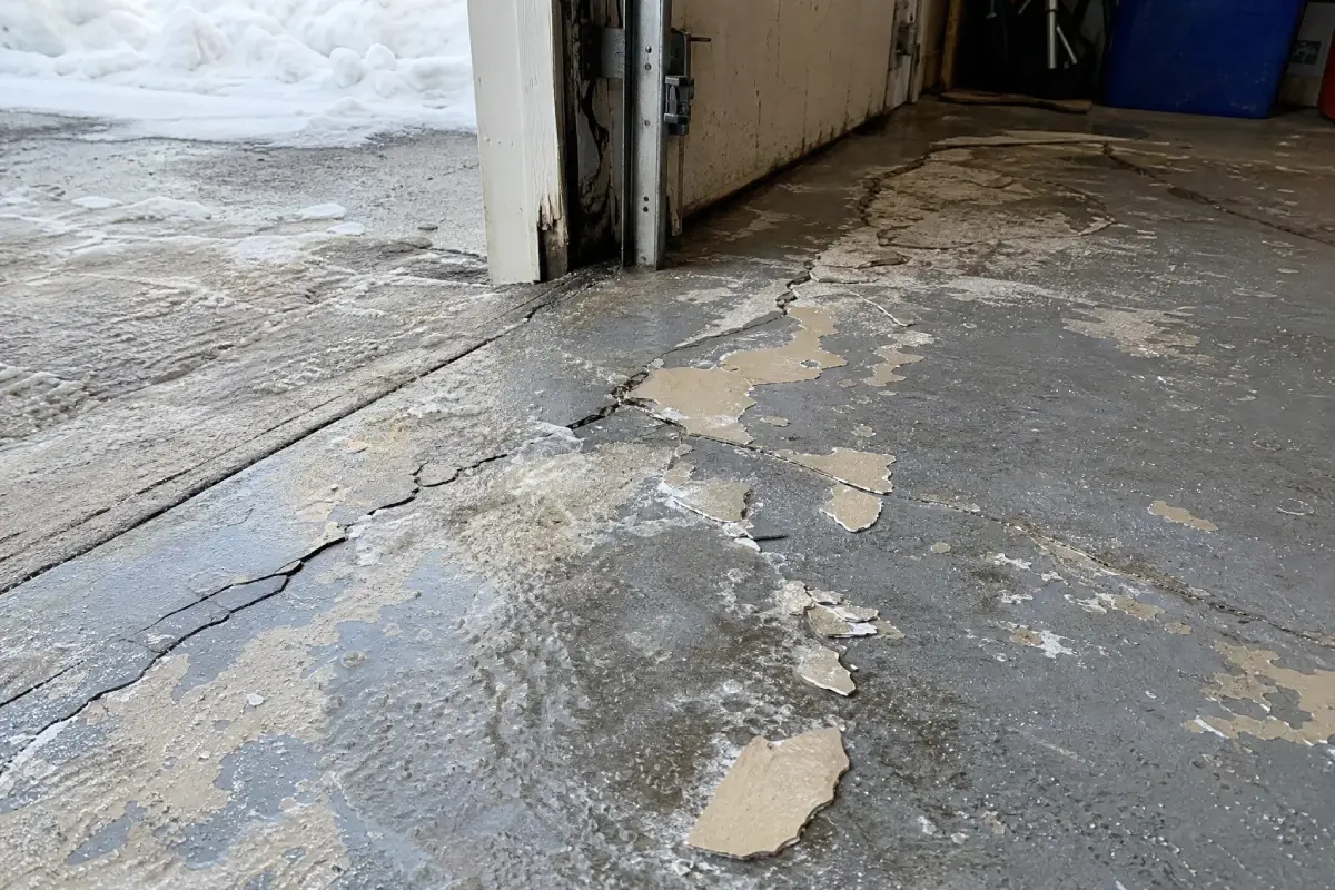 A J&P Coatings garage floor shows damage from water and use, needing repair for safety and a clean look.
